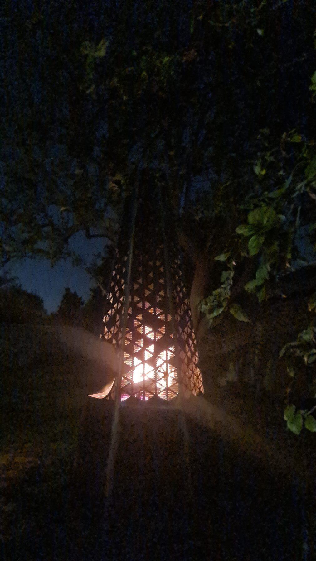 Custom steel fire pit in use at night with flames visible through decorative perforated panel design