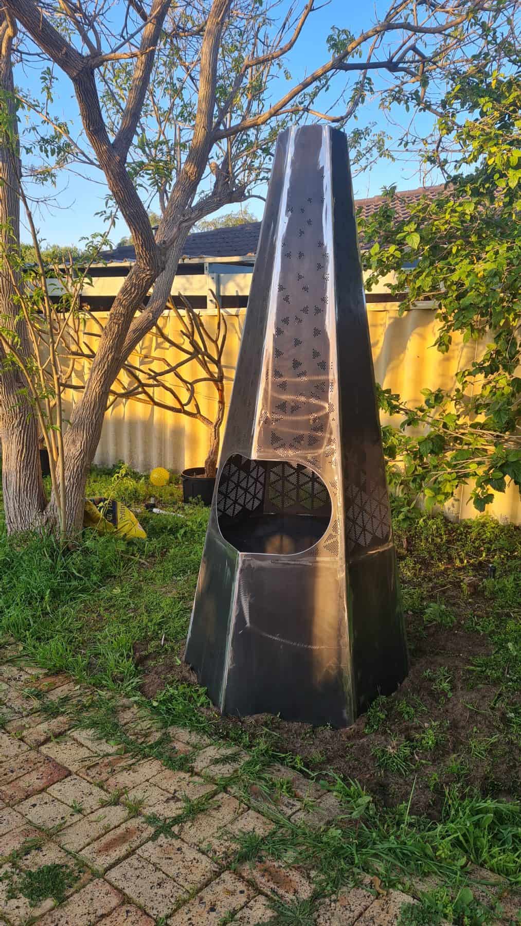 Side view of a custom-fabricated steel fire pit with precision-formed conical structure and matte black powder-coated finish.
