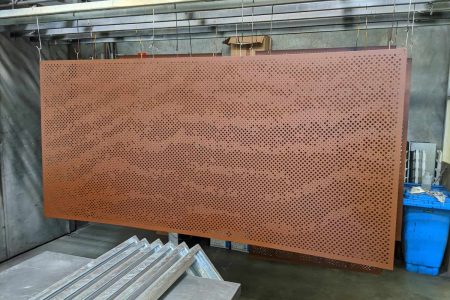 Powder-coated perforated metal panel with bronze finish, used for architectural screening and custom metal fabrication