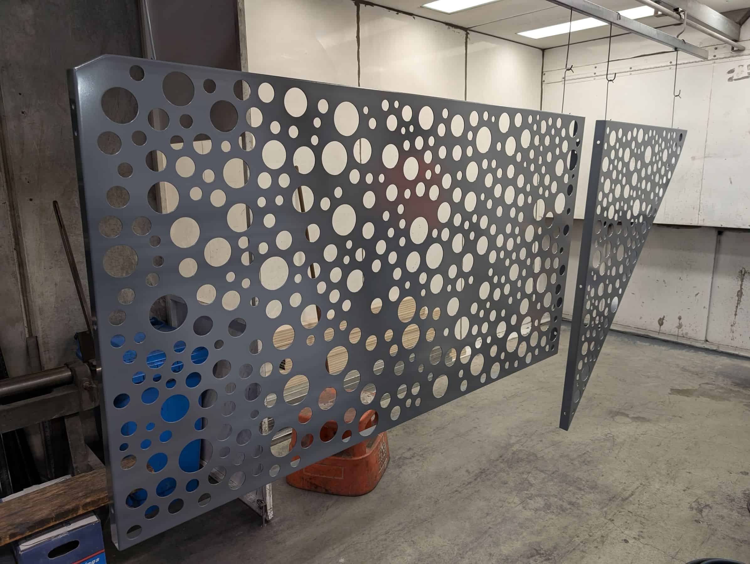 Close-up of a turret-punched metal panel with diverse hole diameters, showing the high-quality finish of the powder coating.